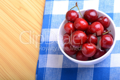 Red ripe cherries in a white bowl