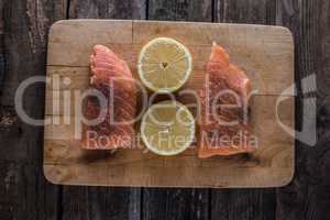 raw salomon on chopping board with lemon