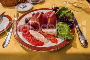 Plate of antepasto including ham and peppers