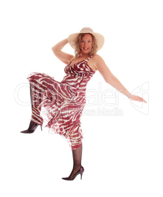Woman dancing in dress and hat.