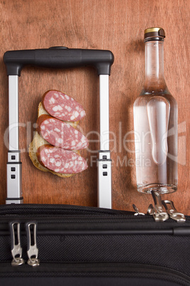 Black suitcase, a bottle of vodka and food