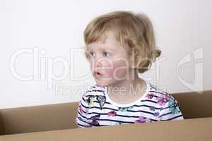 Young girl sitting in cardboard box