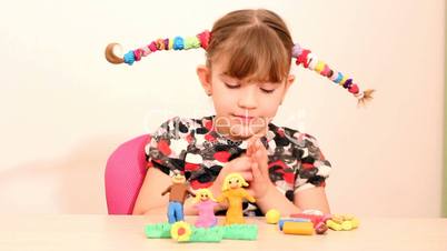 little girl make family figure with plasticine