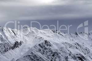 High snowy mountains and sunlight storm sky before blizzard