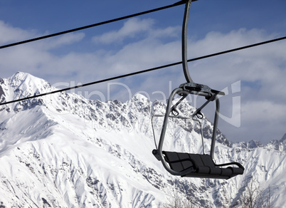 Chair lift in snowy mountains at nice sunny day