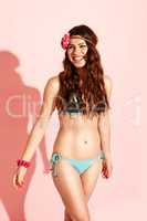 happy hippi model wearing bikini on pink