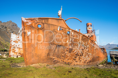 Two rusty old whalers beached beside dock