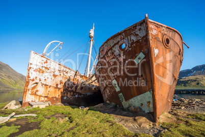 Two rusty old whalers beached on shore