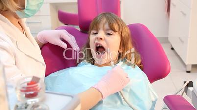 beautiful little girl with open mouth during drilling treatment at the dentist