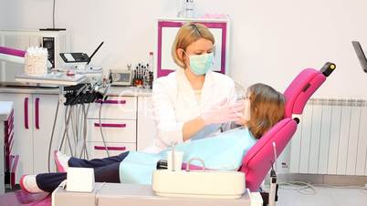 dentist examines teeth a little girl
