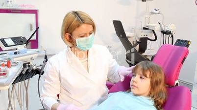 female dentist examines teeth a little girl