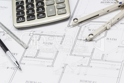 Pencil, Ruler, Compass and Calculator Resting on House Plans