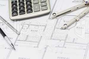 Pencil, Ruler, Compass and Calculator Resting on House Plans