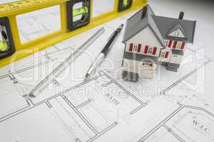 Model Home, Level, Pencil and Ruler Resting on House Plans