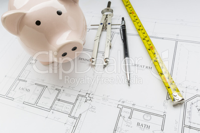 Bank, Compass, Pencil and Measuring Tape Resting on House Plans