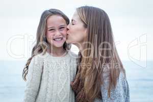 Mother kissing daughter at beach