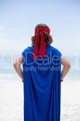 boy in superhero costume at sea shore