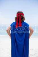 boy in superhero costume at sea shore