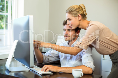 Man and woman discussing while working on computer at office