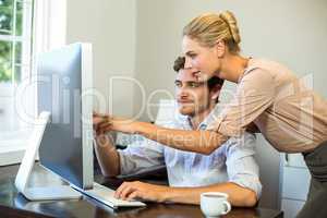 Man and woman discussing while working on computer at office