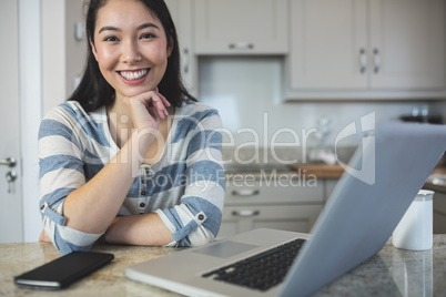 Portrait of young woman sitting with laptop and mobile phone in