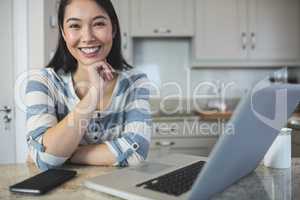 Portrait of young woman sitting with laptop and mobile phone in