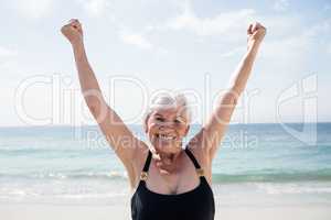 Excited senior woman standing on beach
