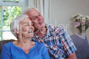 Senior couple looking away while sitting on sofa