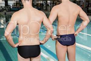 Rear view of swimmers standing by the pool