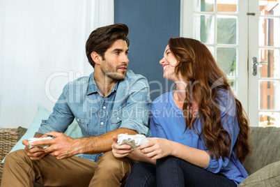 Young couple playing video game while sitting on sofa