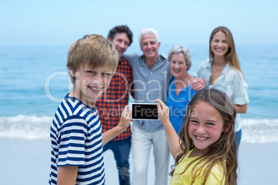 Happy siblings photographing family with smartphone