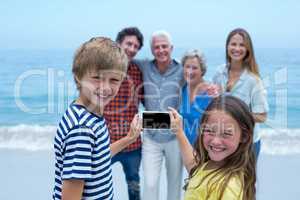 Happy siblings photographing family with smartphone