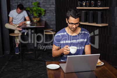 Man using a laptop and drinking coffee