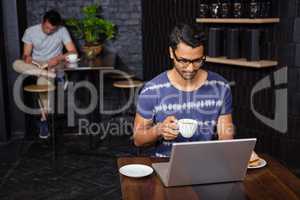 Man using a laptop and drinking coffee