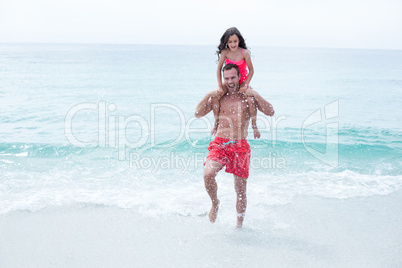 Father enjoying while carrying daughter at beach