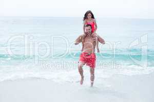 Father enjoying while carrying daughter at beach