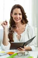 Portrait of happy businesswoman smiling while holding notepad at