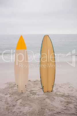 Two surfboard standing in sand