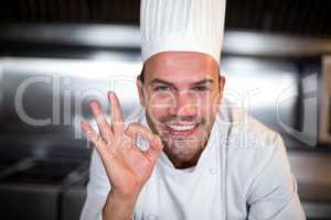Portrait of happy chef showing ok sign in kitchen