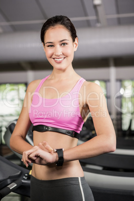 Portrait of happy woman using smart watch on treadmill
