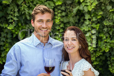 Happy couple holding wineglasses at front yard