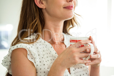 Mid section of woman holding cup of coffee