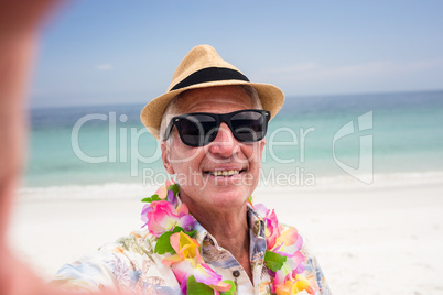 Happy senior man wearing flower garland on the beach