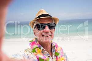 Happy senior man wearing flower garland on the beach