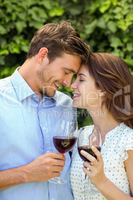 Couple holding wineglasses with eyes closed at front yard