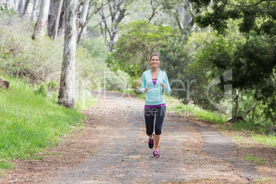 Cheerful young woman jogging in forest