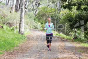 Cheerful young woman jogging in forest