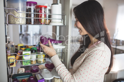Young woman picking a bottle from storage cabinet