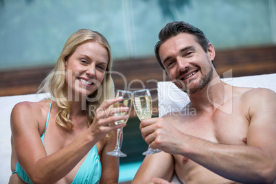 Couple sitting on sun lounger toasting champagne