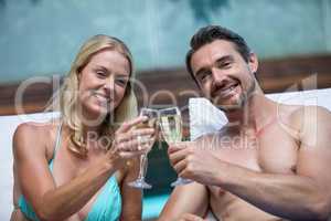 Couple sitting on sun lounger toasting champagne